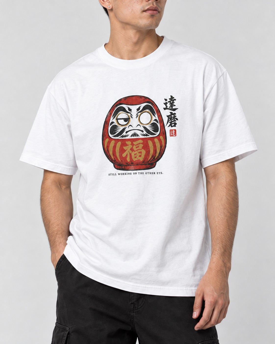 Still Working on the Other Eye Daruma T-Shirt in White, close-up